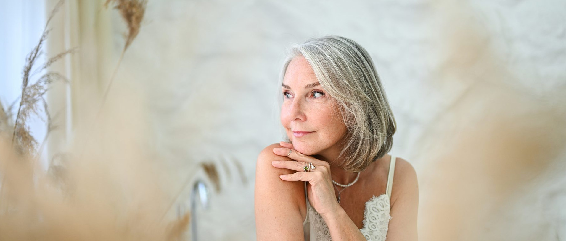 A silver-haired woman resting her hands beneath her chin.