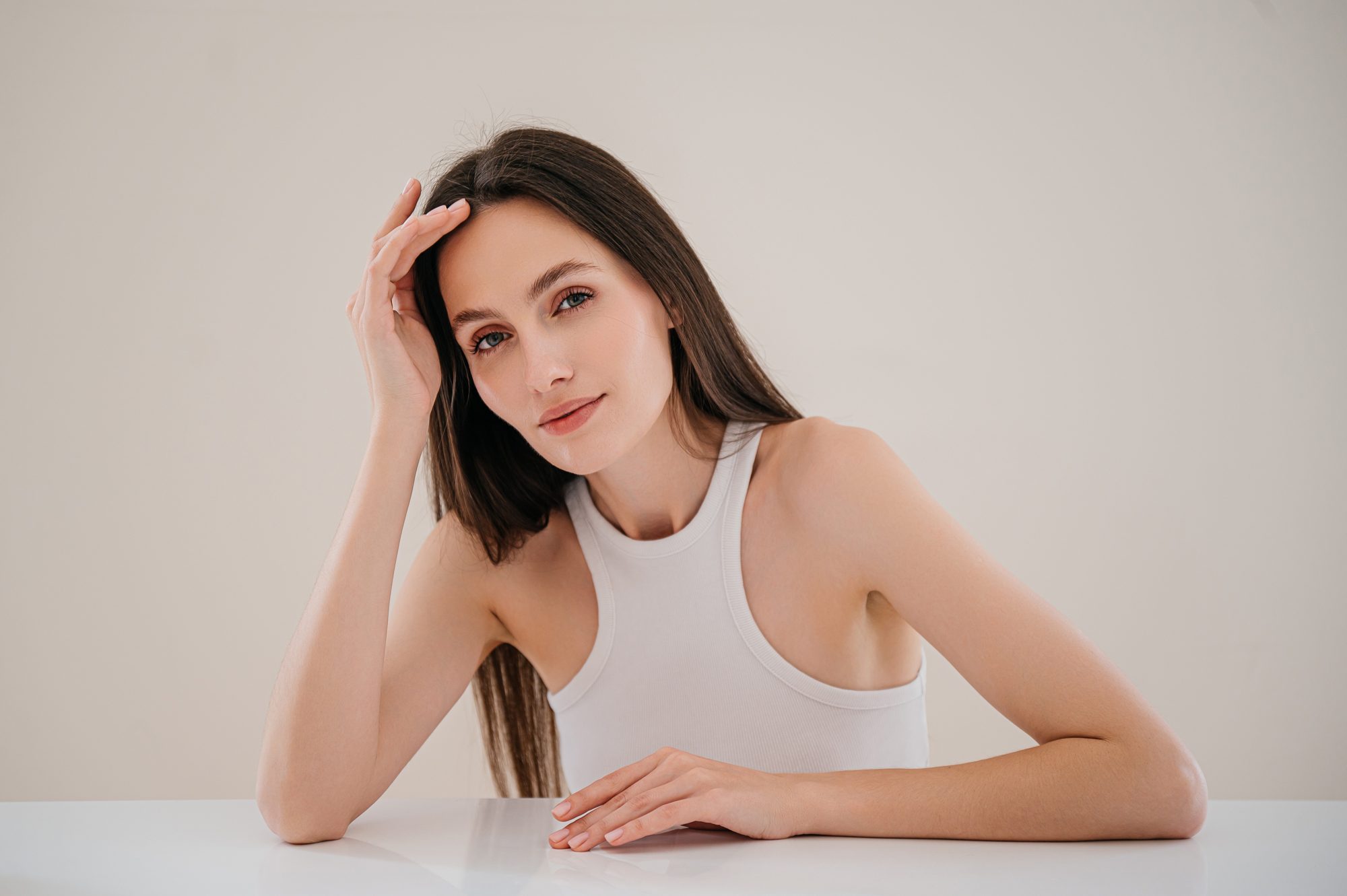 A woman resting on her forearm at a pale table.