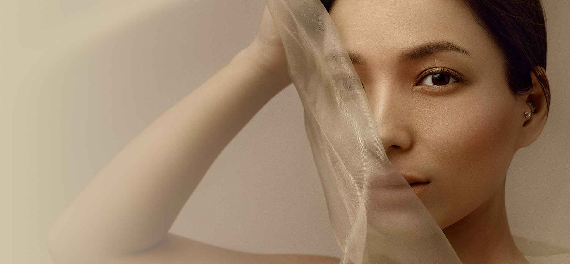 A face behind a sheer veil in warm light.