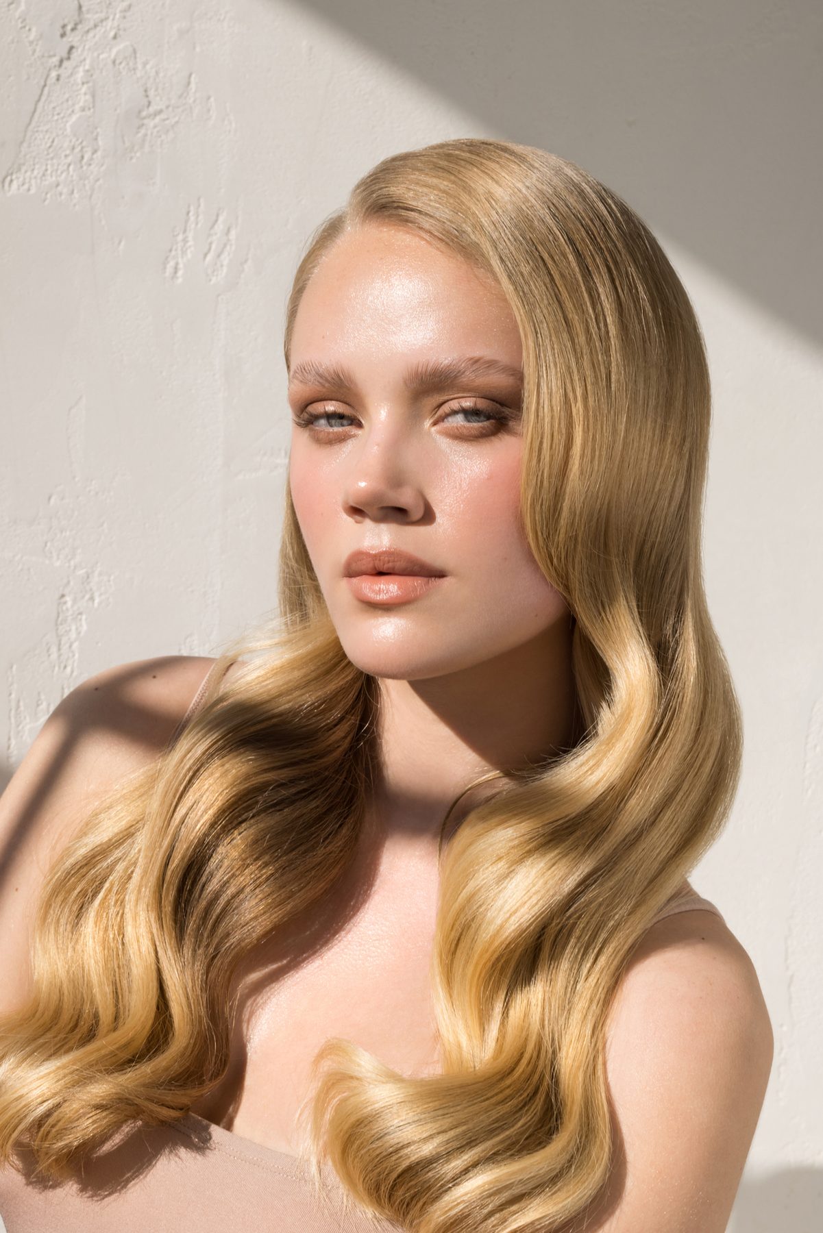 A woman with blonde waves in bright directional light.