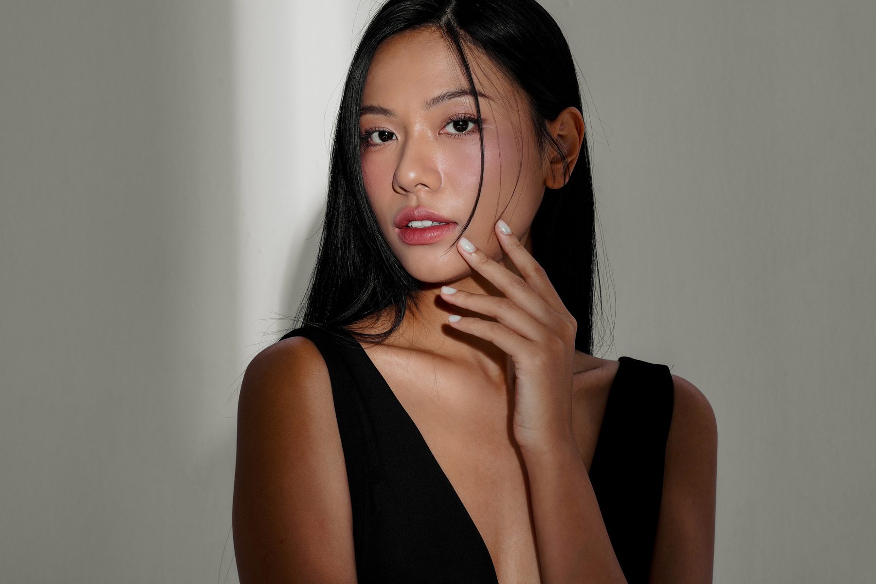 A woman with dark hair resting a hand at her neck.