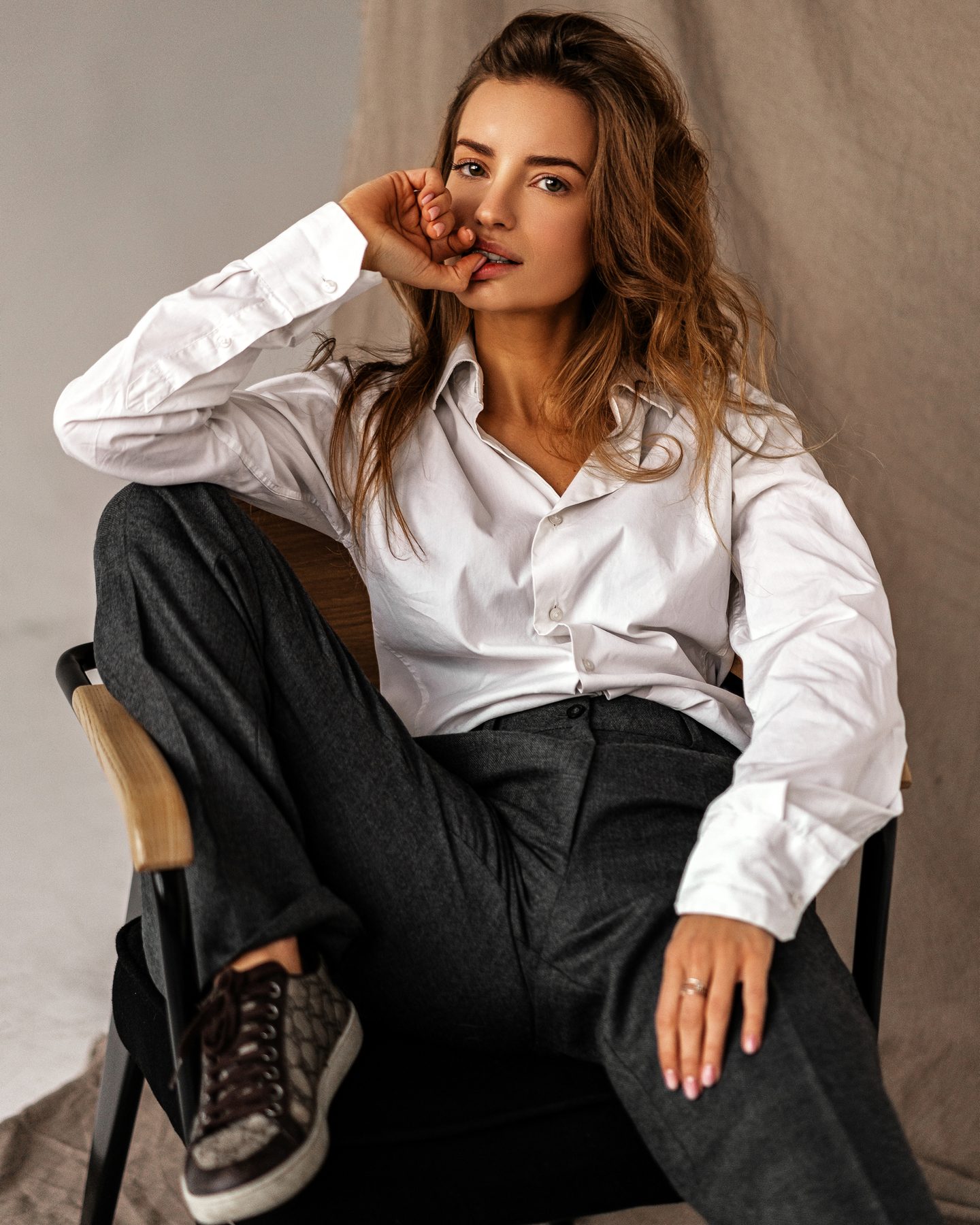 A woman seated in a white shirt and dark trousers.