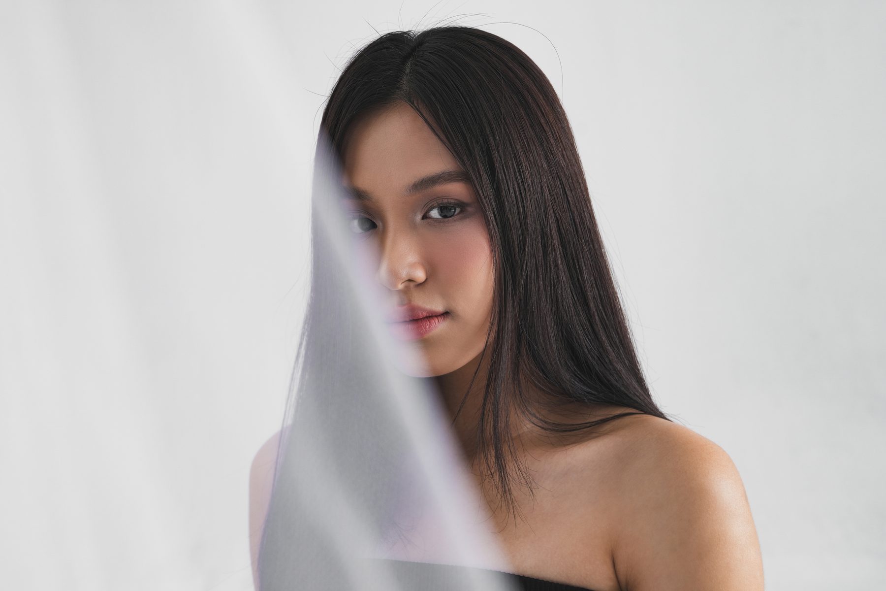 A face softly obscured by a pale sheer veil.